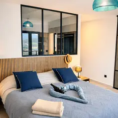 Chambre double avec lit King Size, coussins bleus et tête de lit en bois — Villa Lavandéa