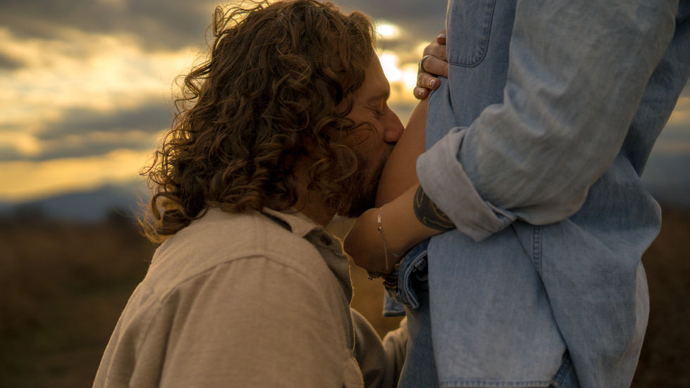 man kissing pregnant belly during sunset maternity session