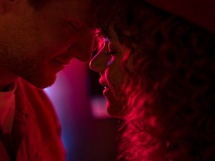 Pareja besandose y celebrando amor y amistad con luces rojas