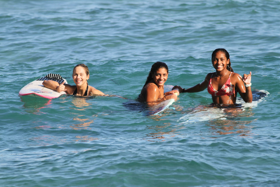 Three women surfers smiling on boards