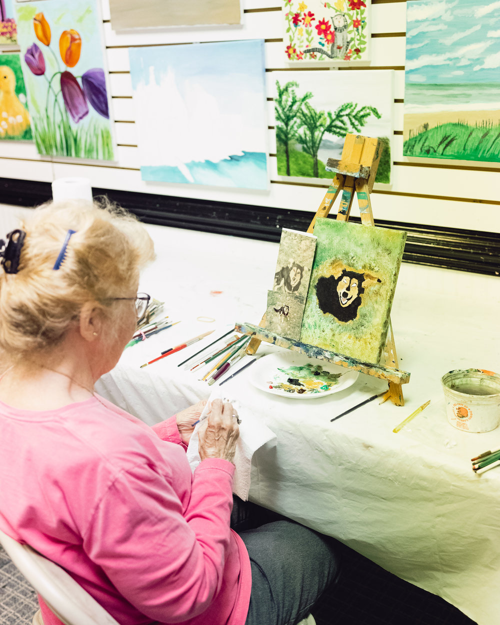 A student painting a bear at an easel at Corner Arts Gallery