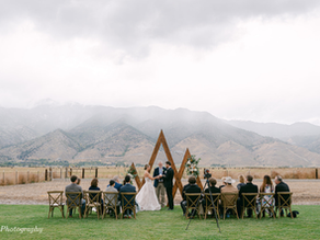 a small wedding ceremony with a cloudy mountain backdrop and green grass