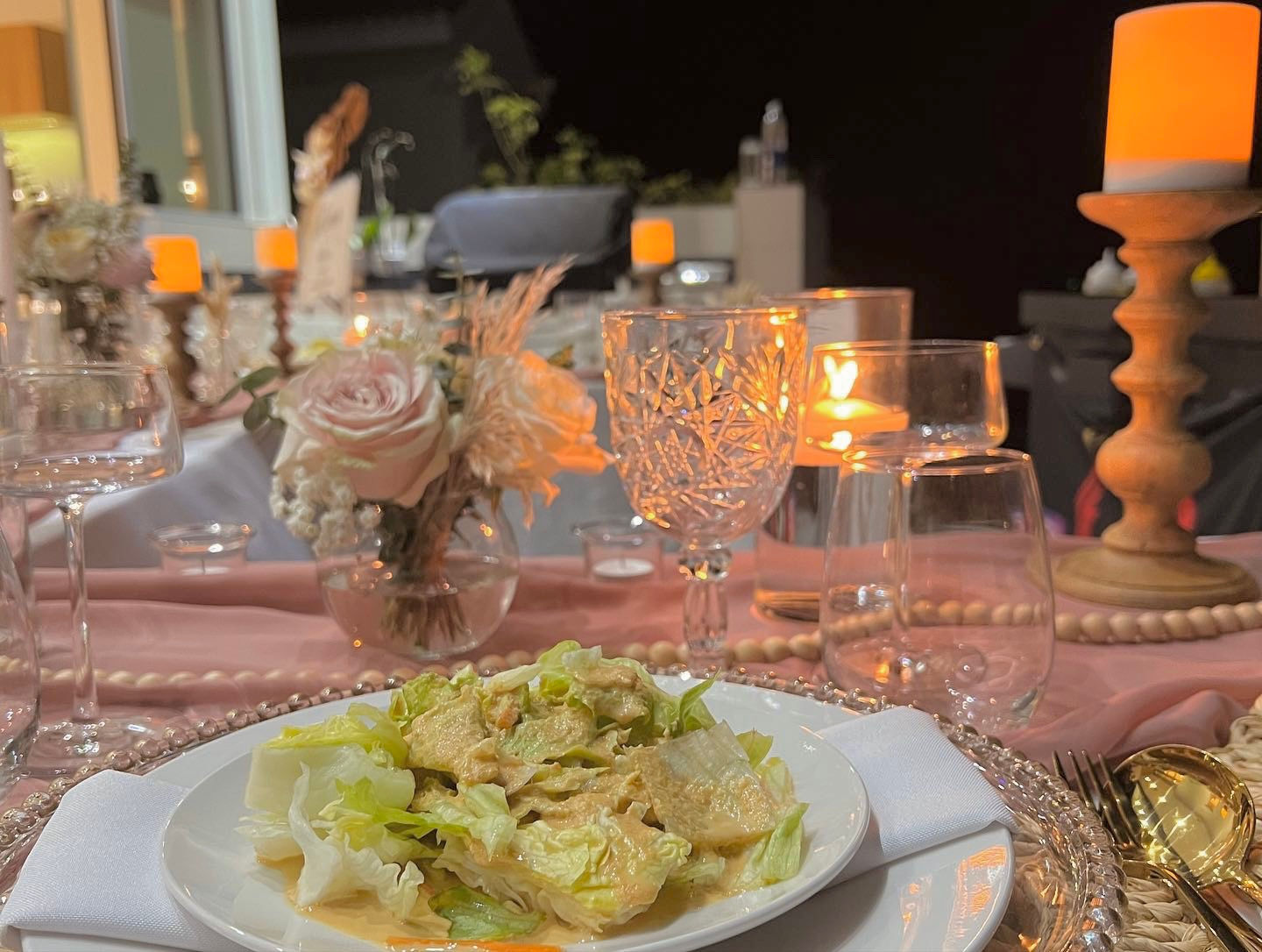 Salad plate on table setting with flowers and candles at night
