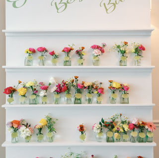 White shelf display with floral arrangements, text says Our Best Brides