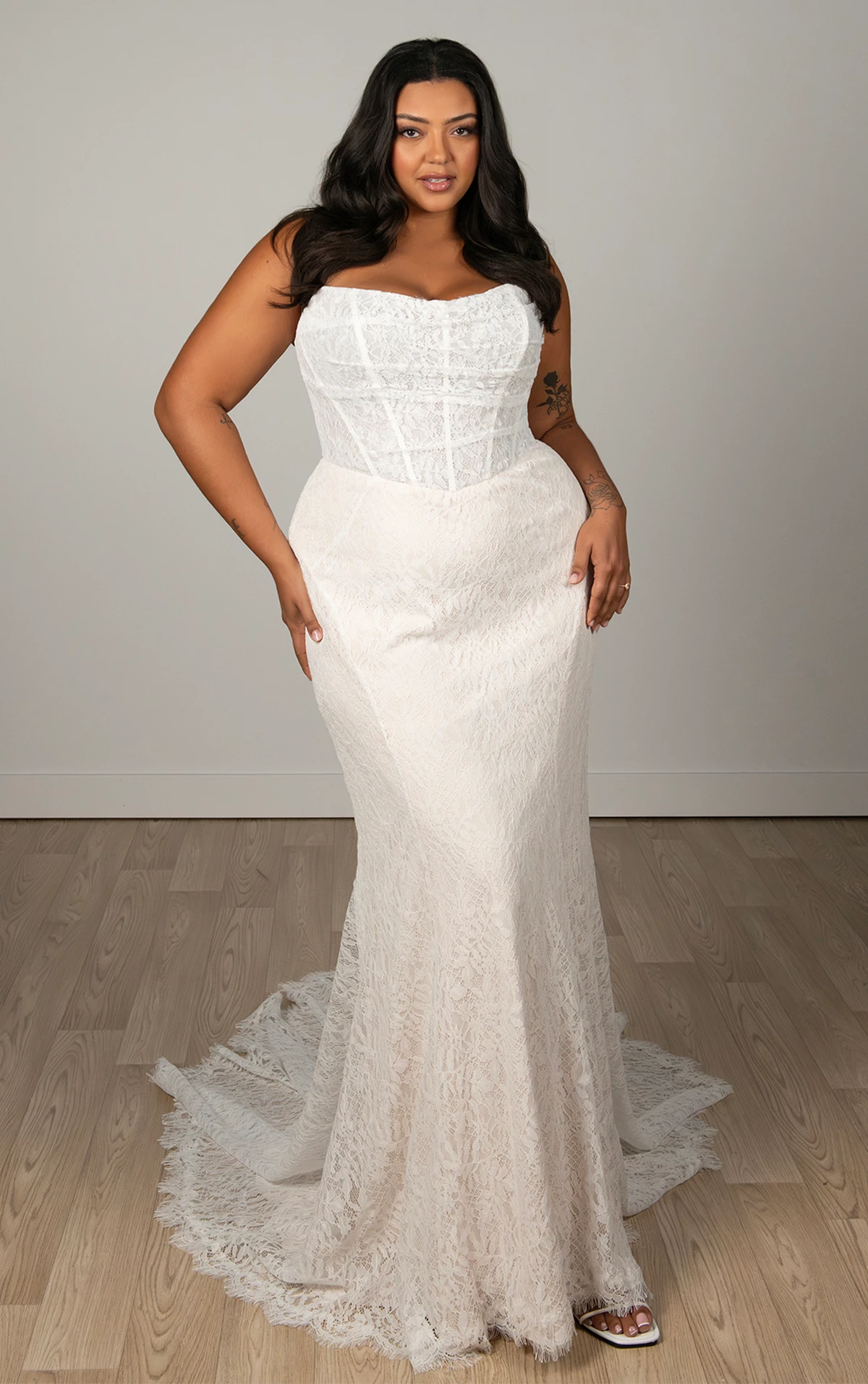 Bride wearing a plus size lace fit-and-flare wedding gown with a structured corset bodice and chapel train