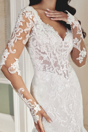 Close-up of a bride wearing a long-sleeve lace fit-and-flare wedding gown with an illusion bodice and intricate floral detailing