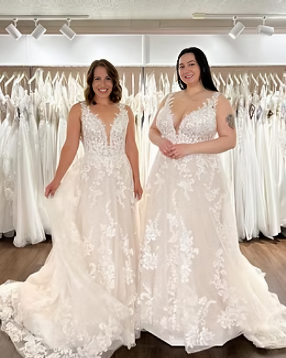Two brides wearing floral lace A-line wedding gowns during a fitting inside Ever After Bridal, showcasing different size options