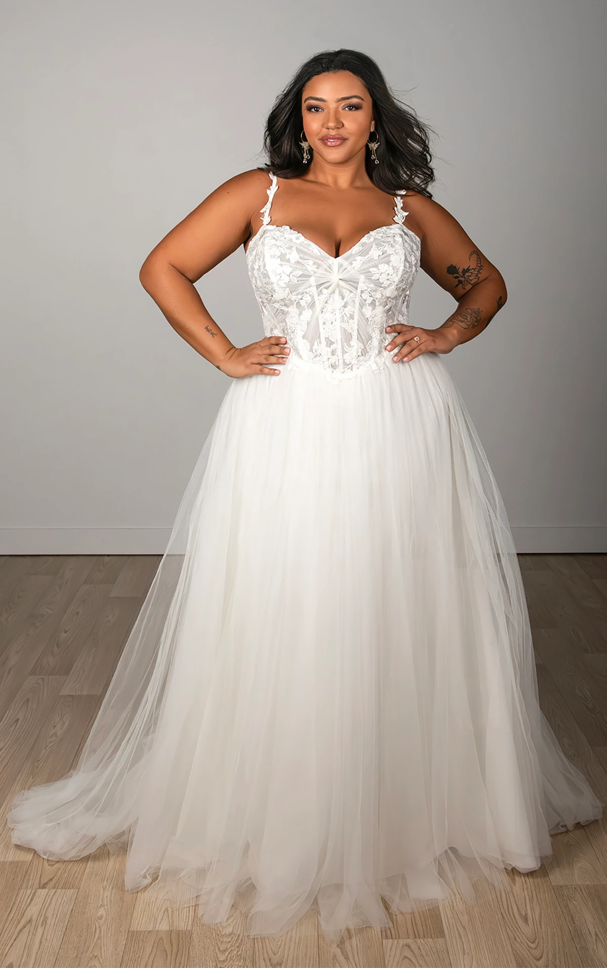 Bride wearing a plus size A-line wedding dress with a beaded corset bodice and tulle skirt in a studio setting