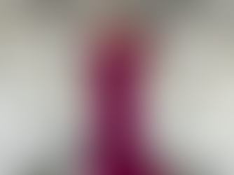 A woman in dark pink posing in front of a dress rack