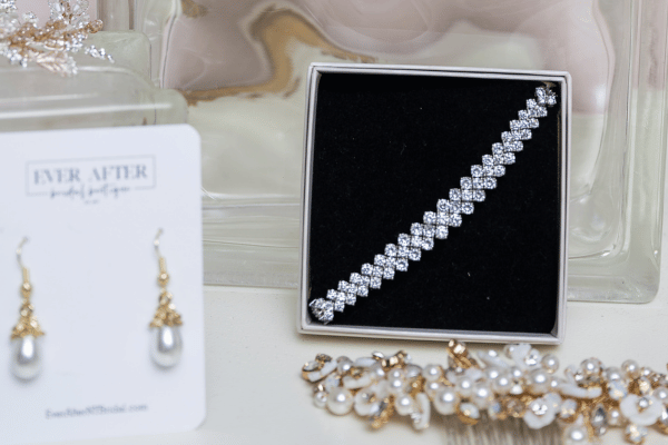 Jewelry display with diamond tennis bracelet in a black box, pearl drop earrings on a card, and gold pearl pieces; MIA MATER text visible