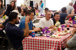 Group of people eating at a table with plates and drinks at an event.