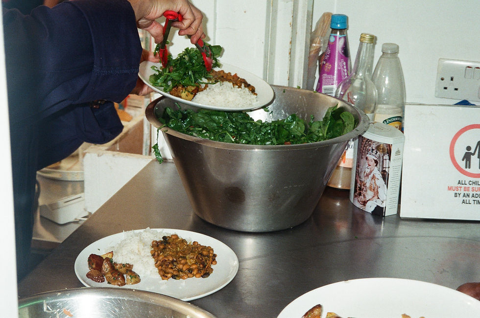 Person serves rice, greens and stew from a large bowl onto plates in a kitchen with bottles and a child-safety sign.