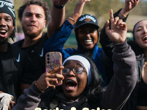 Cheering diverse group outdoors, some raising hands and one filming; text reads WELLBEING SPOTLIGHT and Souls & Soles charity.