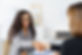 Two businesswomen shaking hands over a desk as they close a deal or partnership, focus to