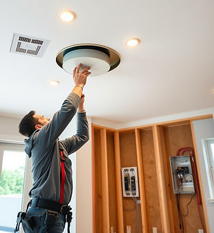 A modern home interior during an electrical remodel, showing an electrician installing rec
