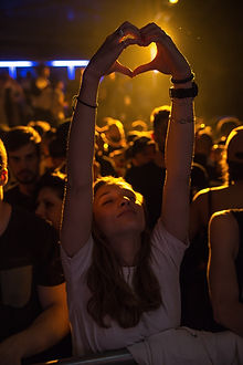 A woman hold her hands up in a disco and shapes it to a heart