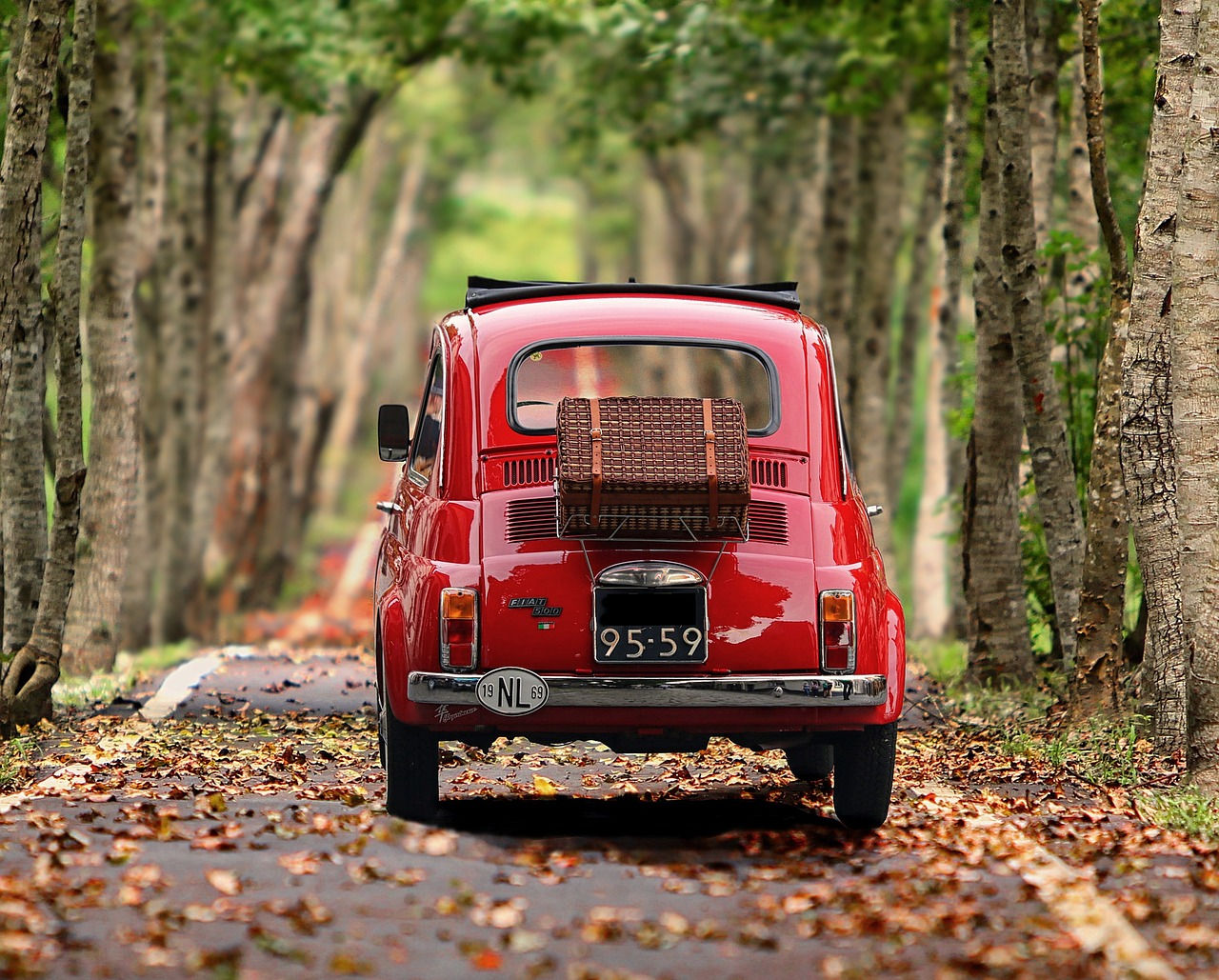 Red Fiat Mini driving through fall leaves