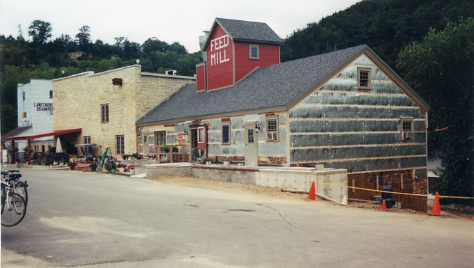 Color photo of the Stone Mill in Lanesboro, Minnesota, showing its stone structure alongside a red “Feed Mill” tower, with the building partially under renovation and surrounded by construction cones.