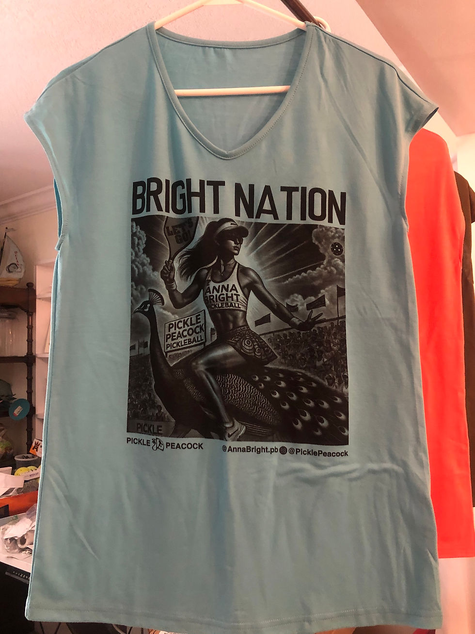 Thumbnail: Anna Bright riding on a peacock. Bright Nation teal tank top for ladies