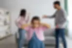 Bé gái bịt tai khi người lớn tranh cãi trong phòng khách, thể hiện tác động của môi trường căng thẳng lên cảm xúc và hành vi của trẻ ADHD.