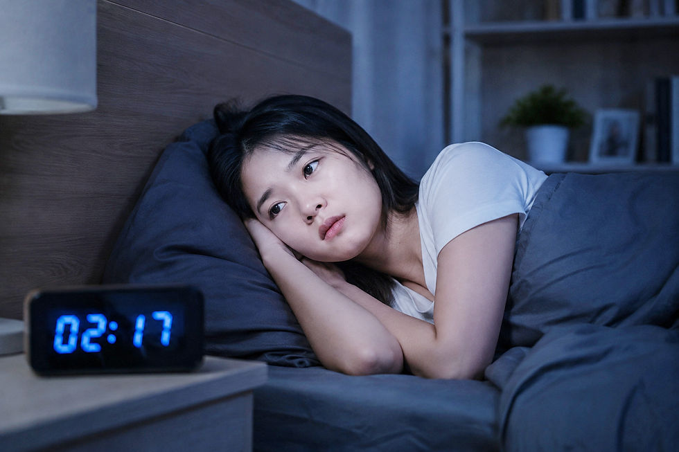 Phụ nữ nằm trên giường lúc 02:17, nhìn trầm tư trong phòng ngủ tối xanh, có vẻ mất ngủ.