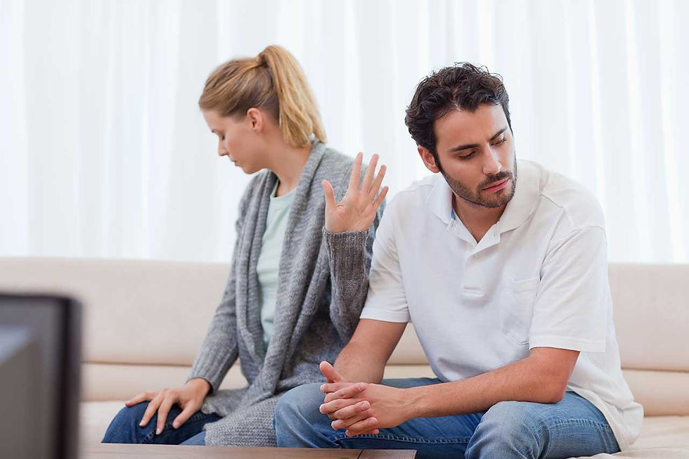 Vợ chồng dần trở nên xa cách và khó giao tiếp trong hôn nhân, người đàn ông và phụ nữ ngồi trên sofa, quay mặt khỏi nhau với vẻ khó chịu. Người phụ nữ giơ tay như thể đang né tránh cuộc trò chuyện.