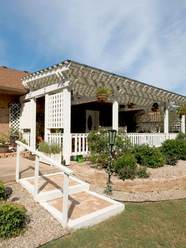 White porch with pergola, railing, and landscaping. A home exterior with Pecan Garden Estate