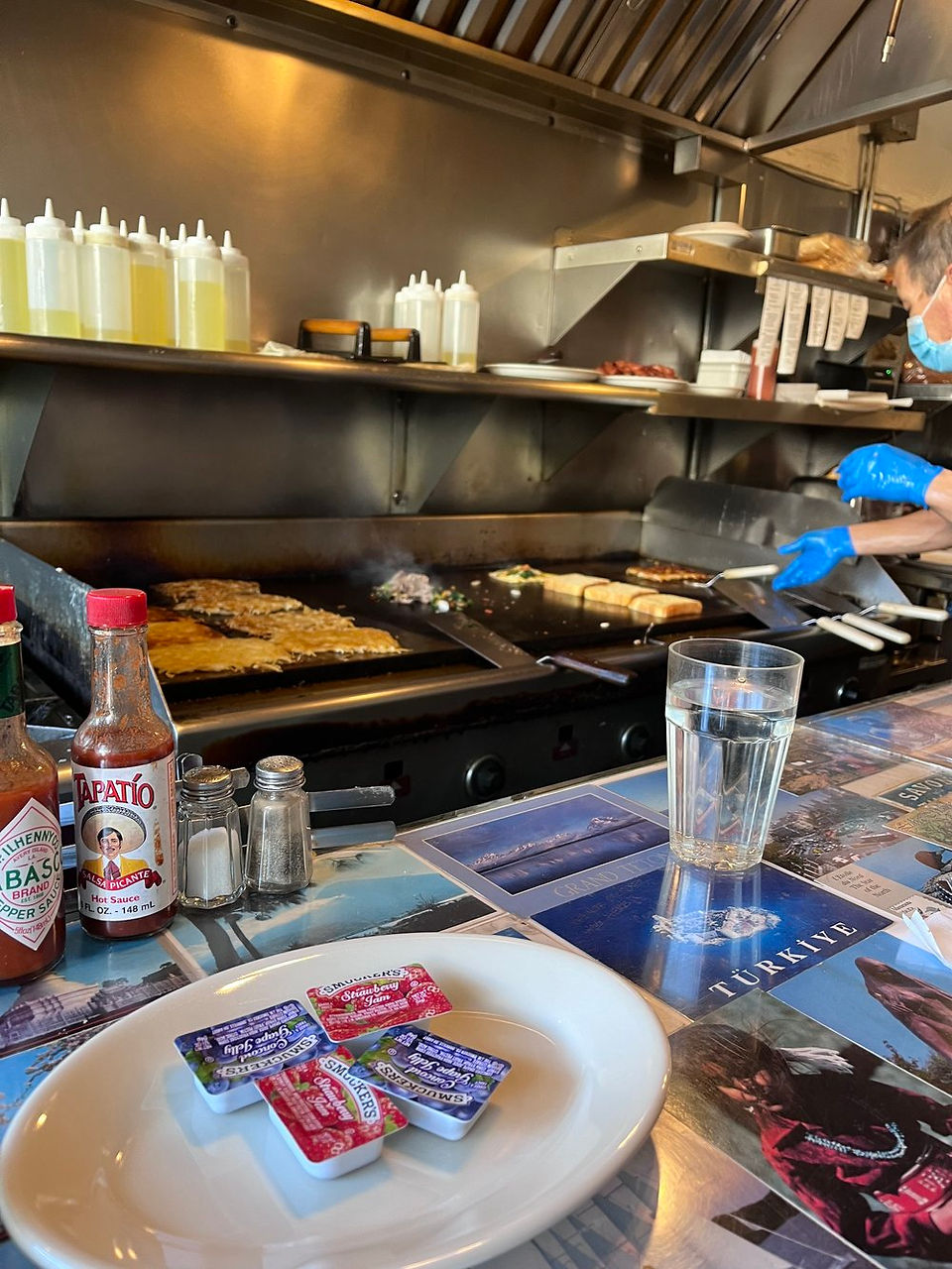 Diner jelly and hot sauce on the counter by a large griddle in Art's Cafe