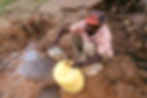 A local man in Wendano collects dirty water from a roadside puddle