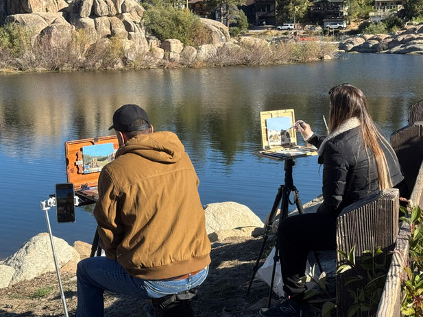 people painting by a lake
