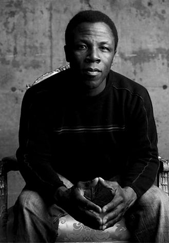 Black and white portrait of Leonard Patton, hands clasped, looking at camera.