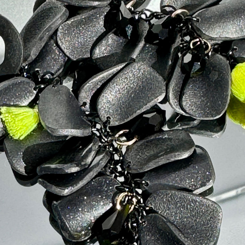 Thumbnail: Grapes Black Asym Earrings Bijoux Vii Mykonos Collection, neon green tassels, black crystals, lying on the table, detail