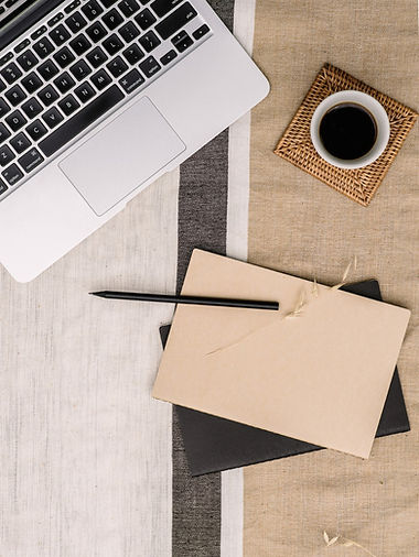 A prepped meeting workspace with laptop, notebook, pen and a coffee.