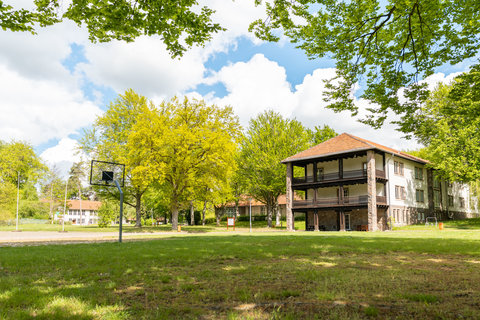 Weitläufige grüne Außenfläche mit Rasen und Naturbereich, ideal für Outdoor-Aktivitäten während Englisch-Feriencamps und Klassenfahrten.