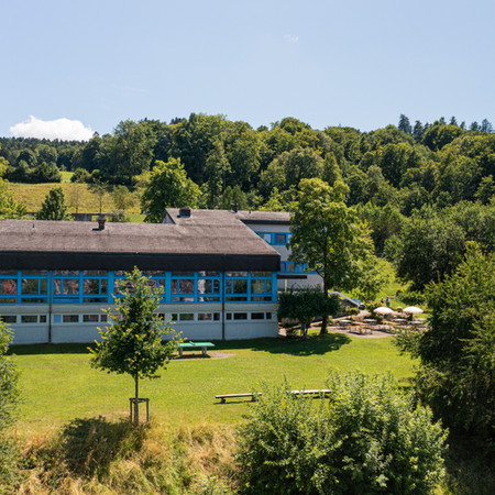 Außenansicht der Jugendherberge St. Gallen im Sommer – moderner Treffpunkt für Englisch-Klassenfahrten mit Native Speakern in grüner Umgebung.