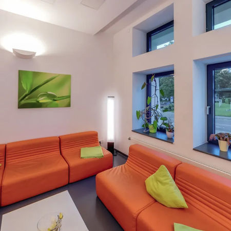 Moderner Aufenthaltsort mit orangefarbenen Sofas für Schüler:innen während einer Englisch-Klassenfahrt.