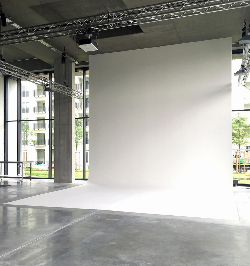 Eye-level view of a spacious and well-lit photography studio with white walls and professional lighting equipment
