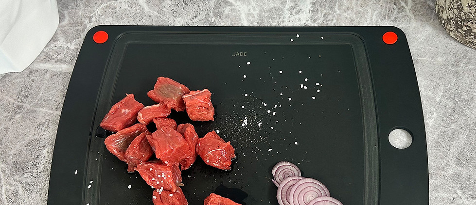 Schwarzes Schneidebrett aus Zellulose-Laminat mit Gemüse darauf