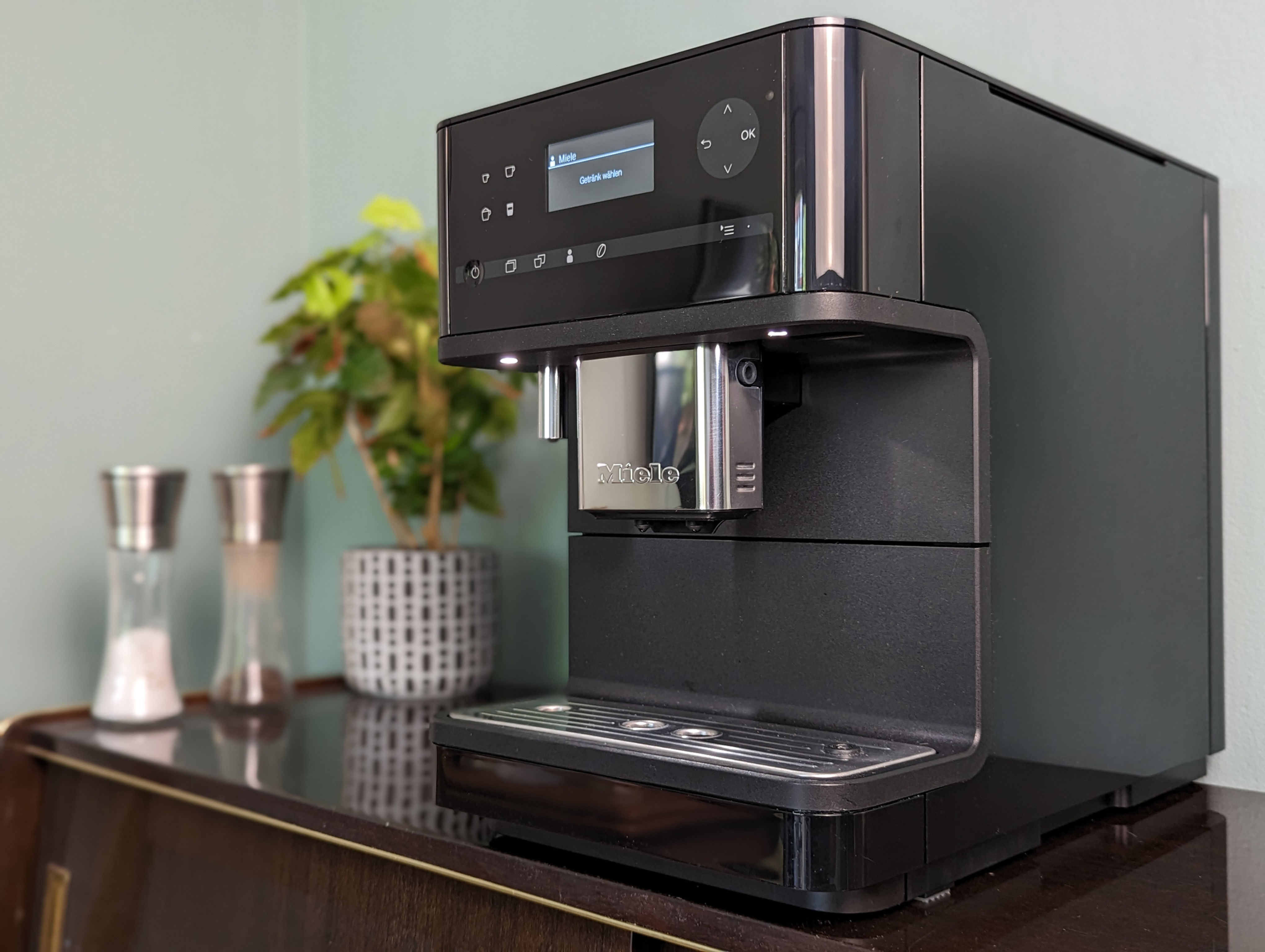 Miele CM6350 Black Edition Kaffeevollautomat in schwarz refurbished by BeansBerlin mit einer Pflanze im Hintergrund