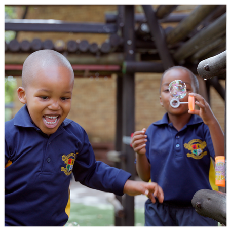 Happy preschoolers having fun blowing bubbles outdoors in Pretoria’s Moot area.