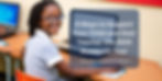 School girl with a big smile on her face at school using a laptop
