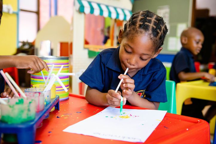 Grade 1 child engaging in creative sensory play by blowing paint, improving motor control and focus.