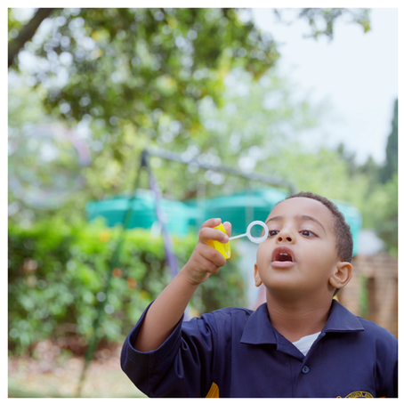 Happy preschoolers having fun blowing bubbles outdoors.