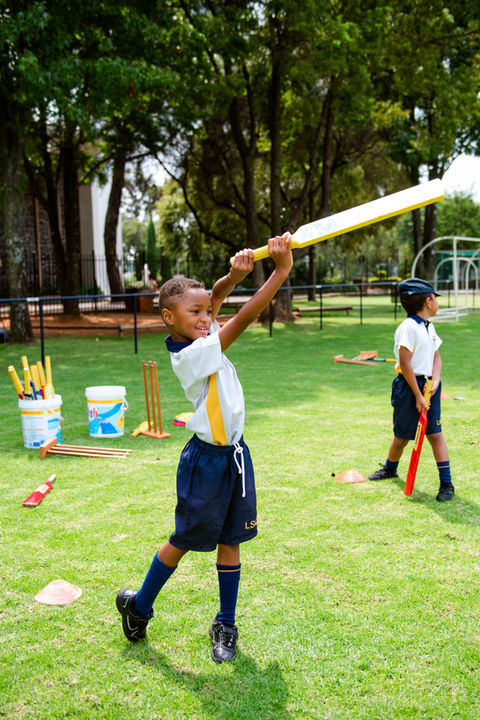 A grade 1 learner learning to play cricket on the field near a school at DIRCO.