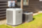 Heating and air conditioning system external units on grass in a house backyard.jpg