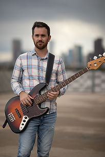 Luke Hardcastle Bass Guitar and Vocals in Dear Luna Band posing on rooftop in Denver Colorado downtown 
