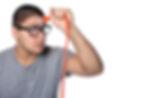 Young man with glasses holds an orange plug near his forehead, suggesting a humorous idea. He wears a gray shirt against a white background.