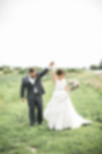 bride and groom dancing in a grass field with flower bouquet and striped dress