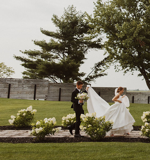 bride and groom walking into little lights on the lane with studio bloom iowa bridal bouquet