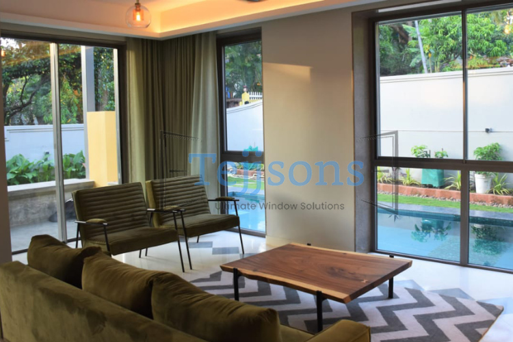 Modern living room with motorised windows overlooking a pool.